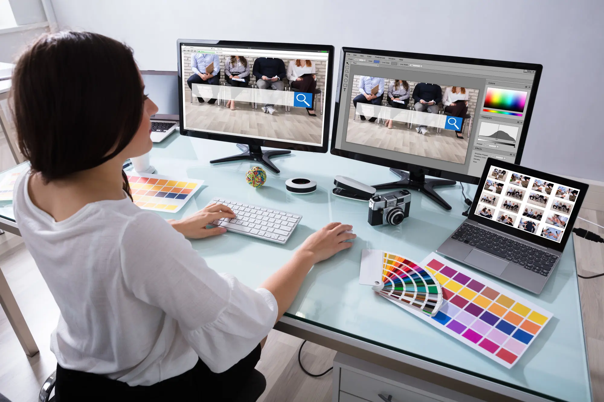 A woman sitting at a desk with two monitors in front of her.